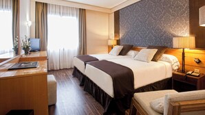 Habitación de hotel con una cama grande, mesitas de noche, un escritorio y una silla.
