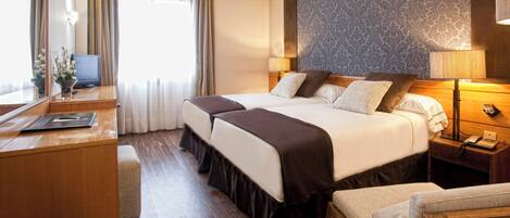 A hotel room with a large bed, bedside tables, a desk, and a chair.