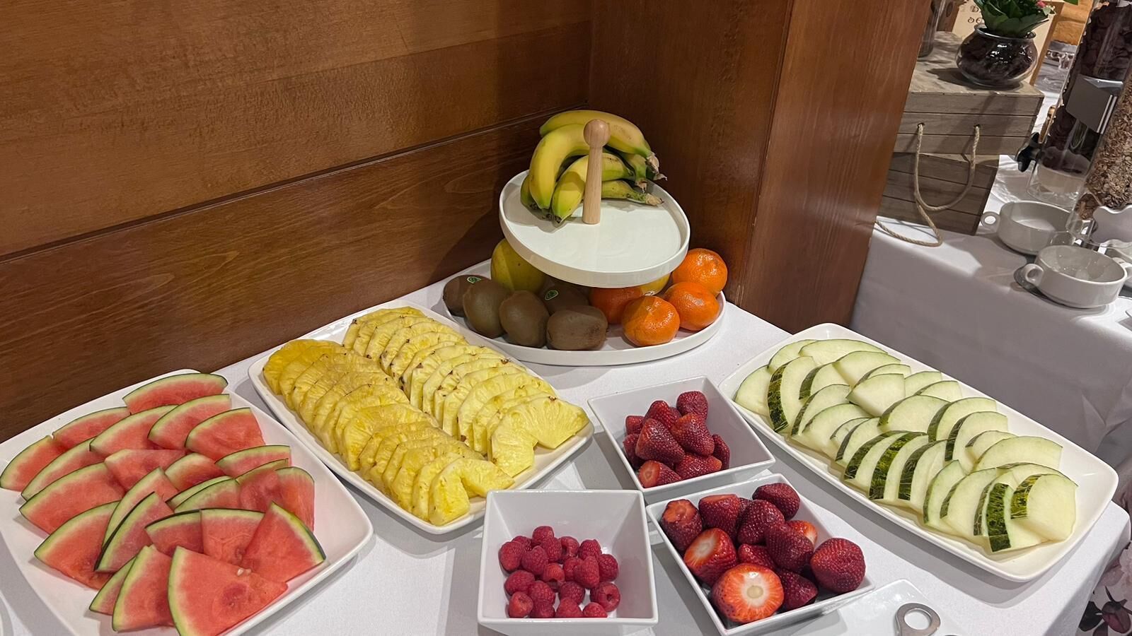 A buffet table with various fruits and a three-tiered fruit display.