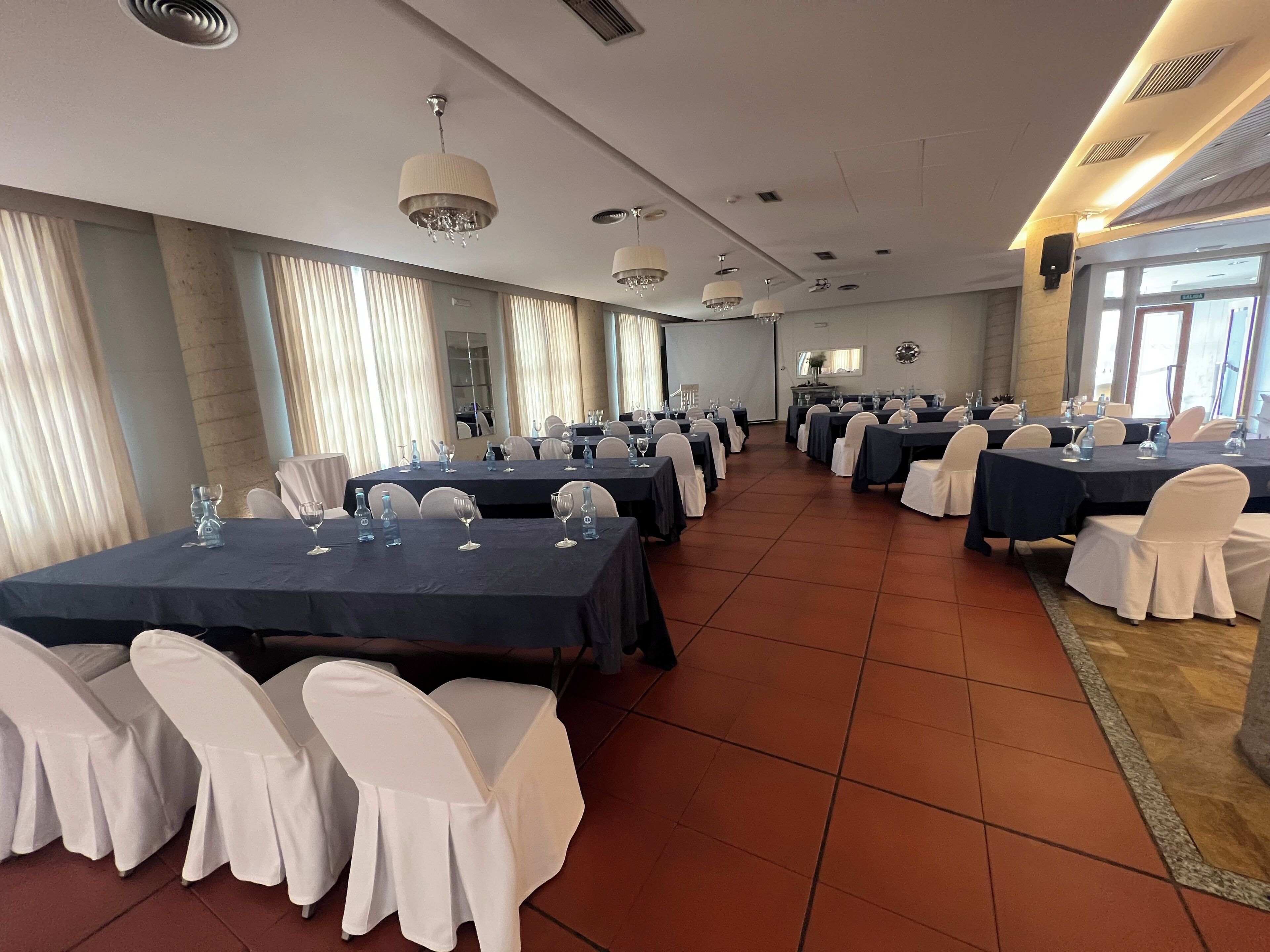 A conference room with multiple tables and chairs, equipped with water bottles and glasses.