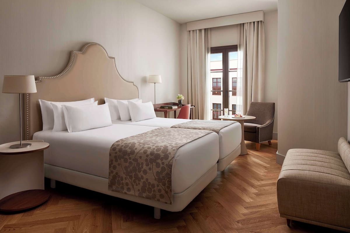 Una habitación de hotel con una cama grande, dos mesitas de noche, un escritorio, una silla y un sofá.