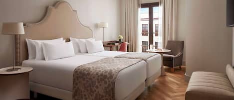 Una habitación de hotel con una cama grande, dos mesitas de noche, un escritorio, una silla y un sofá.