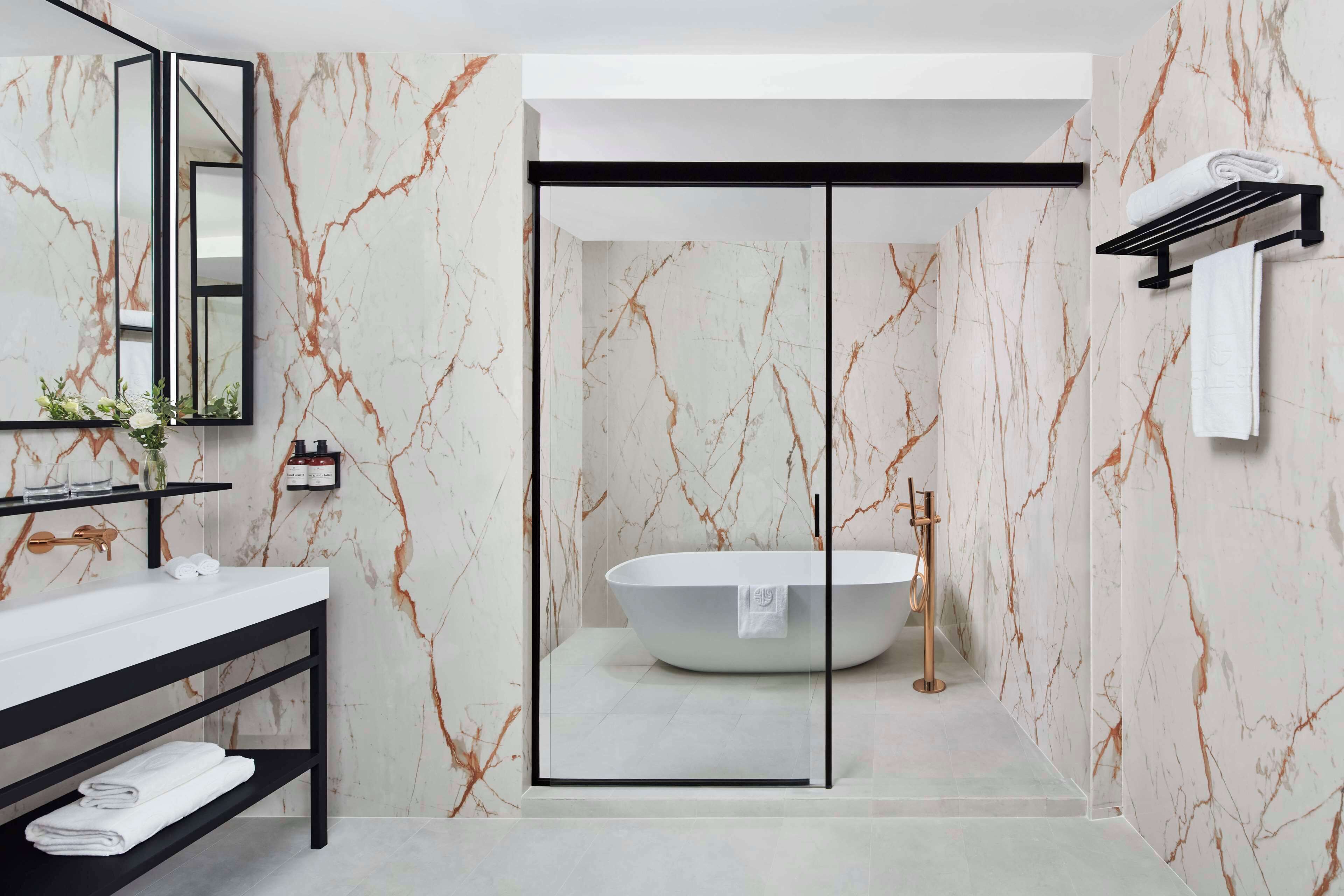 Un bagno moderno con una vasca freestanding, box doccia in vetro e un mobile lavabo nero con schienale in marmo.
