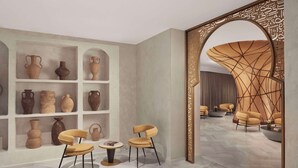 A room with shelves displaying pottery, a seating area with chairs, and a decorative wall with intricate patterns. - NH Collection Palacio de Córdoba (Córdoba)