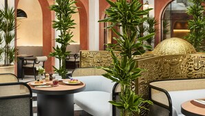 A modern interior with round tables, comfortable seating, and decorative plants. - NH Collection Palacio de Córdoba (Córdoba)