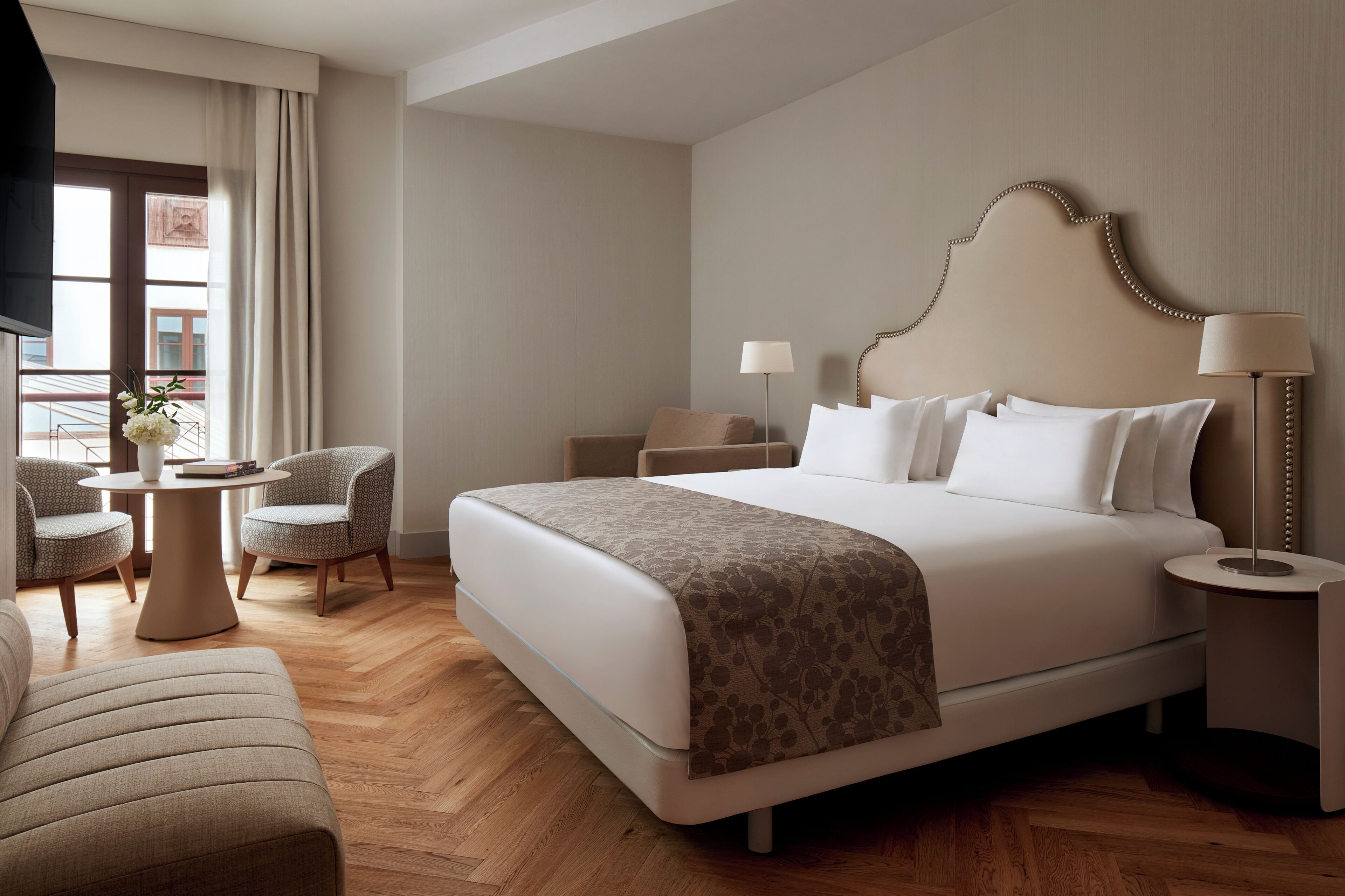 Ein Hotelzimmer mit einem großen Bett, zwei Nachttischen, einem Sessel, einer Couch und einem kleinen Tisch mit einer Lampe.