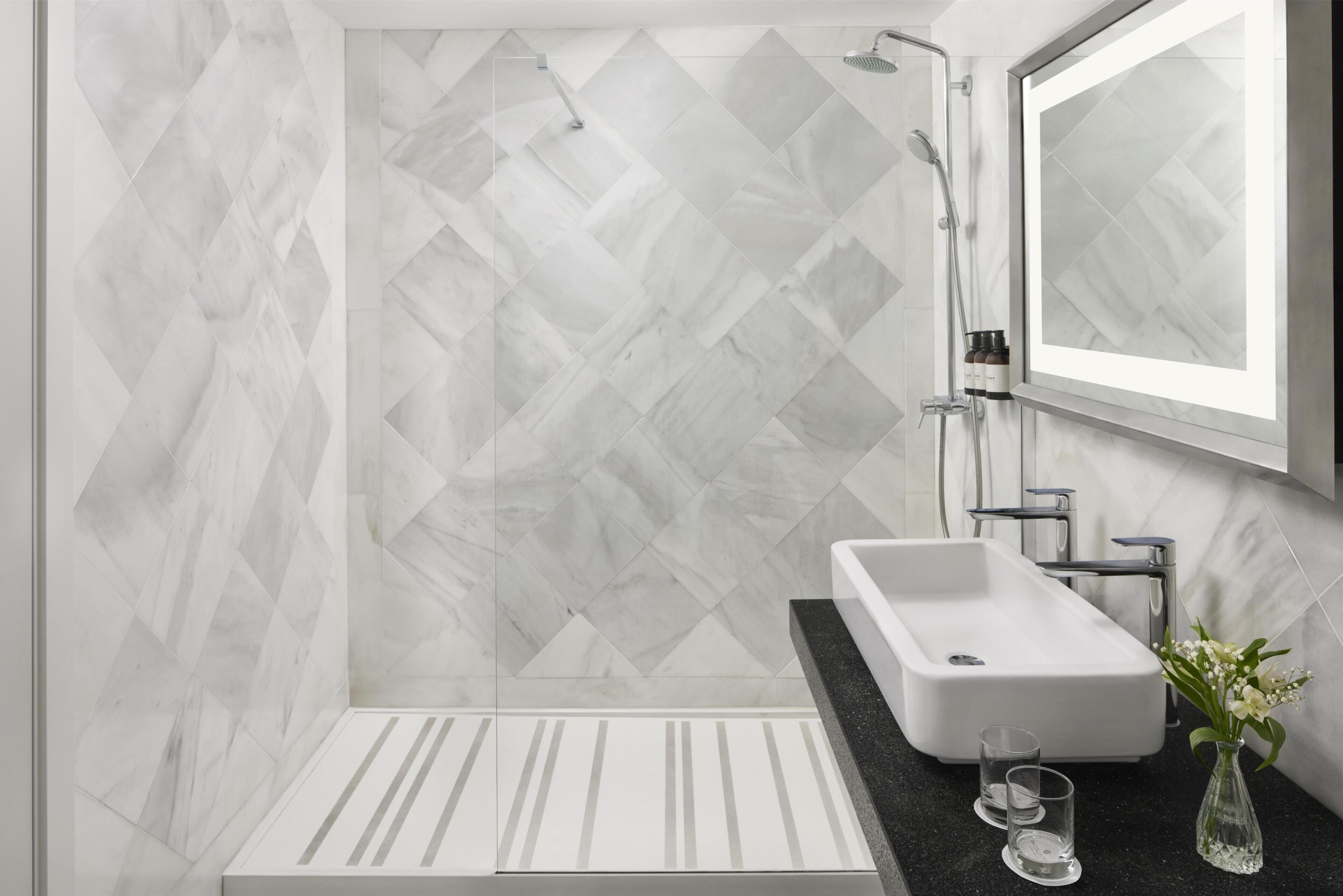 Un baño moderno con ducha, lavabo y espejo.