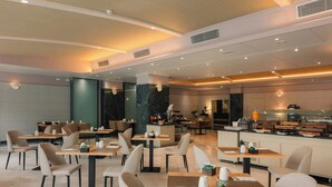 Un restaurante moderno con varias mesas y sillas, una zona de cocina y una barra.