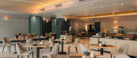 A modern restaurant with multiple dining tables and chairs, a kitchen area, and a bar.