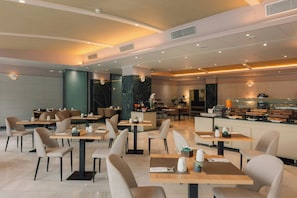 Un restaurante moderno con varias mesas y sillas, una zona de cocina y una barra.