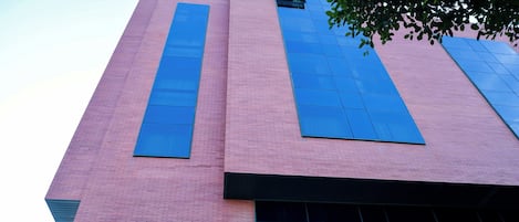 A building with a pink brick facade and large blue windows.