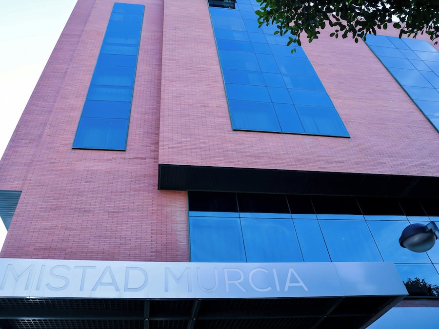 A building with a pink brick facade and large blue windows.