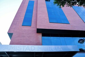 Un edificio con fachada de ladrillo rosa y grandes ventanales azules.