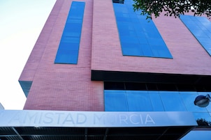 Un edificio con fachada de ladrillo rosa y grandes ventanales azules.