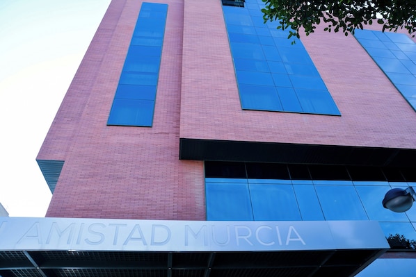 Un edificio con fachada de ladrillo rosa y grandes ventanales azules.