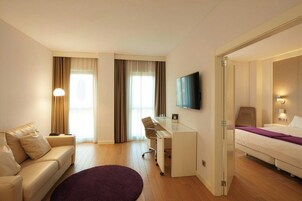 Habitación de hotel con sofá, escritorio, televisión y cama.