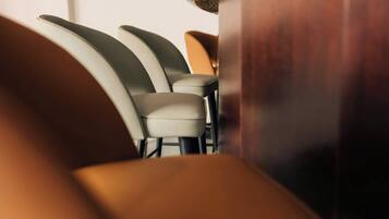A row of chairs with a wooden table in between, suggesting a seating arrangement in a restaurant or cafe.