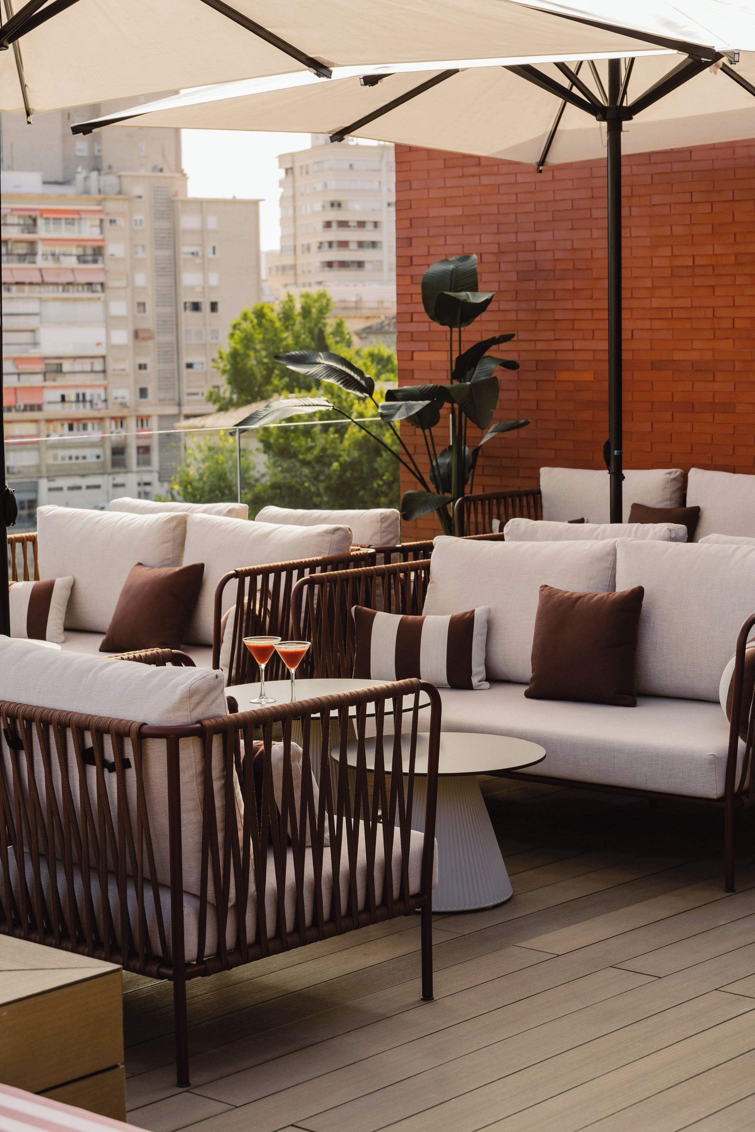 An outdoor seating area with wicker furniture and a brick wall backdrop.