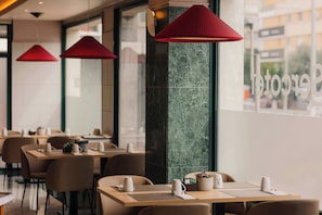 A modern restaurant with multiple tables, red pendant lights, and a view of the street outside. - Sercotel Amistad Murcia (Murcia)