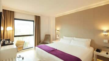 Habitación de hotel con cama, escritorio, silla, mesitas de noche y ventana.