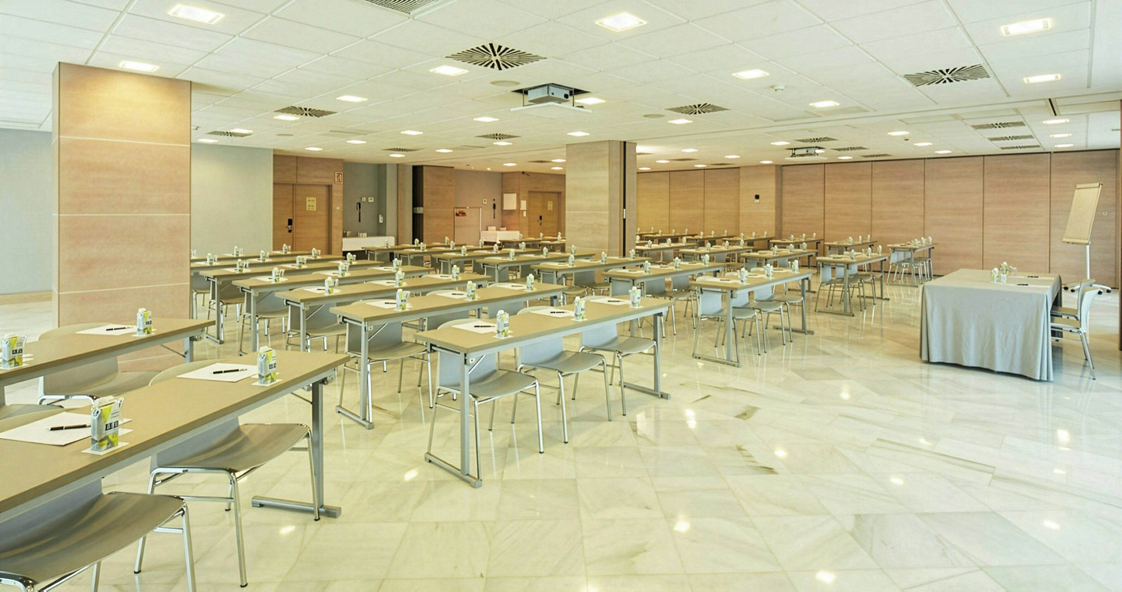 Un salón de conferencias con varias mesas y sillas, equipado con tarjetas de identificación y botellas de agua.