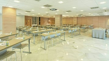 Un salón de conferencias con varias mesas y sillas, equipado con tarjetas de identificación y botellas de agua.
