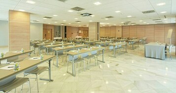 Un salón de conferencias con varias mesas y sillas, equipado con tarjetas de identificación y botellas de agua.