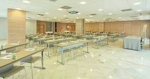 Un salón de conferencias con varias mesas y sillas, equipado con tarjetas de identificación y botellas de agua.