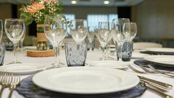 Una mesa de comedor dispuesta con platos blancos, copas de vino transparentes y cubiertos de plata.