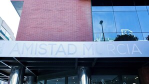 Un edificio con una amplia ventana vertical de vidrio azul y un letrero que dice 'AMISTAD MURCIA' en la parte inferior.