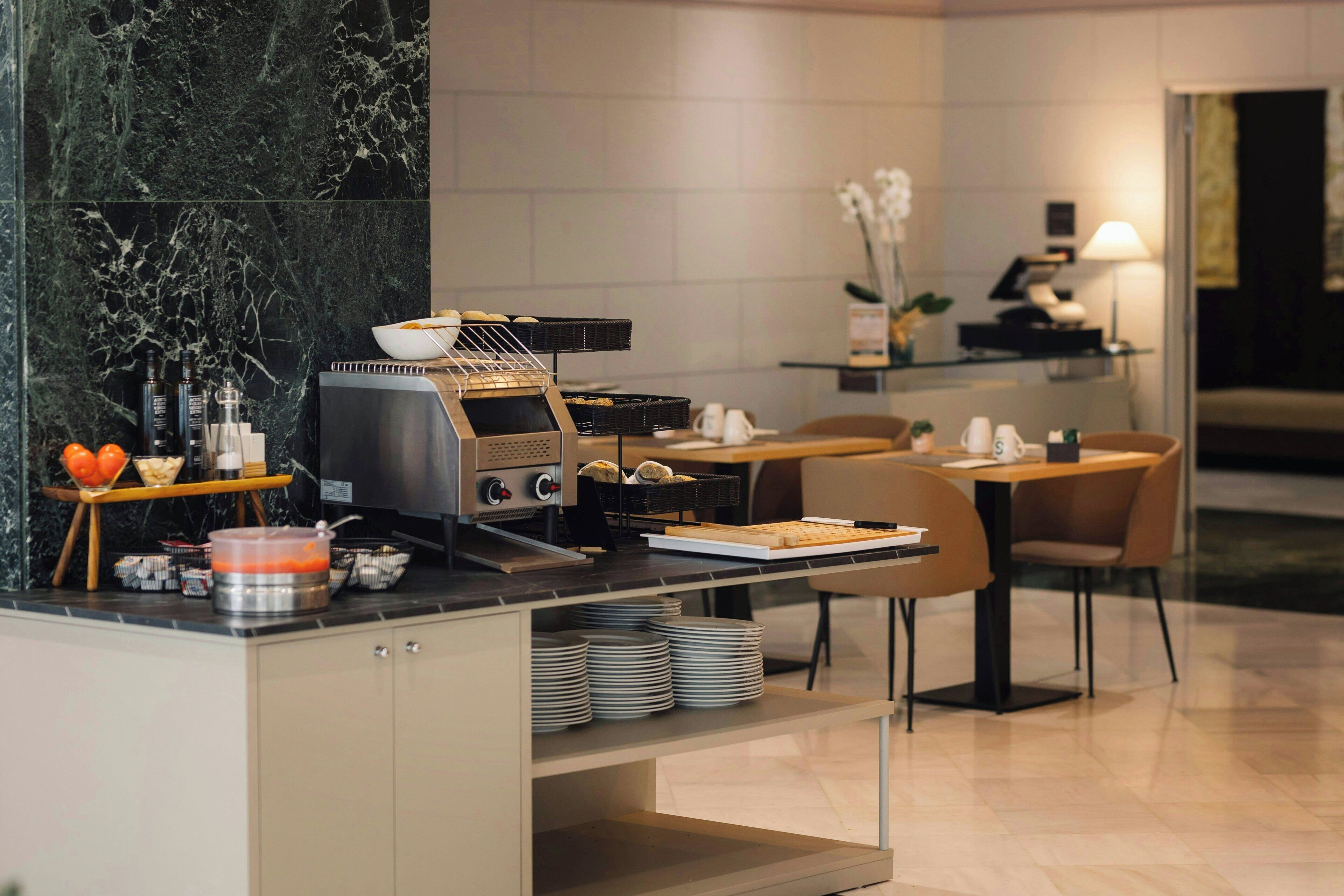Una cocina moderna con estufa integrada, cafetera y zona de comedor con sillas y mesa.