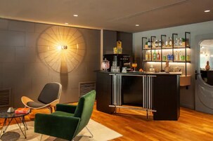 Un área de bar moderna con una lámpara redonda en la pared, una barra y un estante con varias botellas.