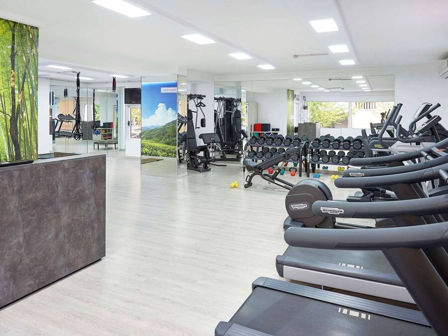 Un gimnasio moderno con cintas de correr, máquinas de pesas y una recepción.