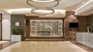 Eine moderne Hotelhalle mit Weinkeller, einer Rezeption und einer großen, runden Leuchte an der Decke.