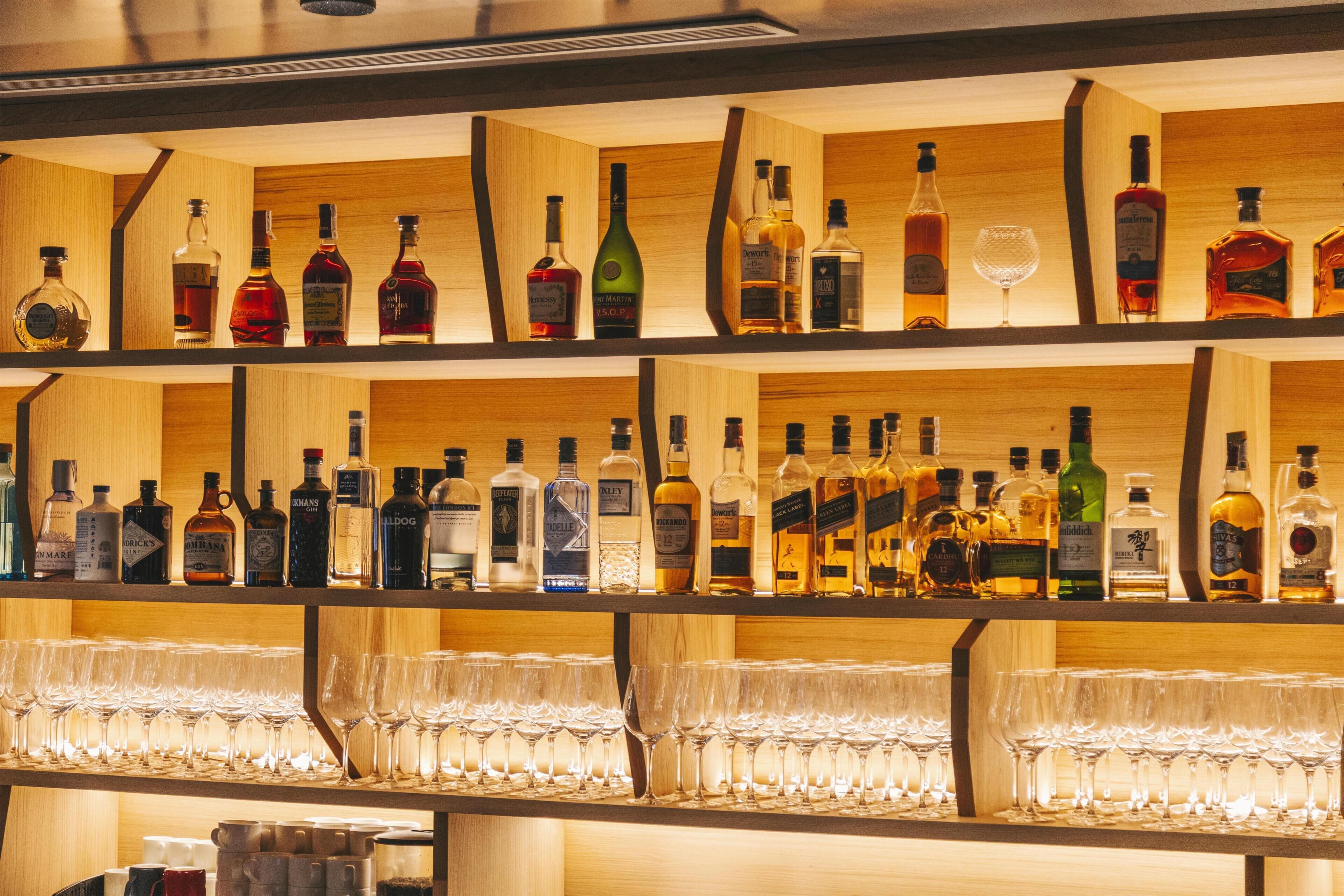 A bar with multiple shelves of liquor bottles and glasses.