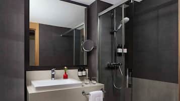 Un baño moderno con un espejo grande, un lavabo, una ducha y un perchero para toallas.