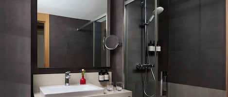 A modern bathroom with a large mirror, a sink, a shower, and a towel rack.