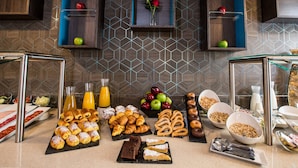 Un bufé de desayuno con pasteles, frutas y bebidas.