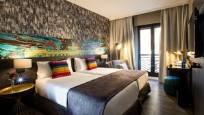 Una habitación de hotel con una cama grande, dos mesitas de noche, un televisor y un balcón con cortinas.