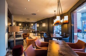 A modern interior with a sofa, dining table, and chairs, a kitchen area, and large windows. - Leonardo Boutique Hotel Madrid (Madrid)