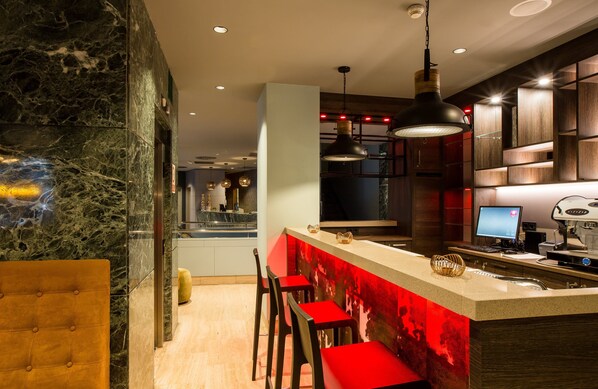 A modern kitchen with a marble backsplash, red bar stools, and a built-in coffee machine. - Leonardo Boutique Hotel Madrid (Madrid)