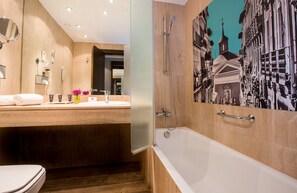 A modern bathroom with a wooden vanity, a large mirror, a bathtub, and a wall-mounted phone. - Leonardo Boutique Hotel Madrid (Madrid)