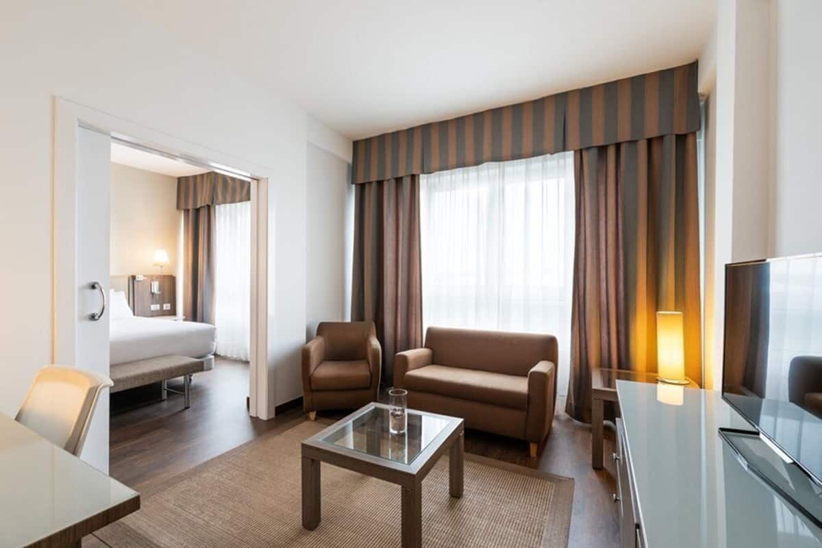 Ein Hotelzimmer mit einem Bett, zwei Sofas, einem Couchtisch, einem Fernseher und einem Schreibtisch.