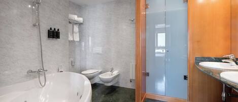 Une salle de bain moderne avec une baignoire sur pieds, des toilettes et un bidet.