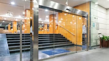 Une entrée d’hôtel moderne avec des portes en verre, un escalier menant au hall d’accueil et une enseigne indiquant « Eurostars Hotels ».