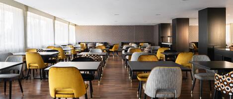 A modern dining area with multiple tables and chairs, large windows, and a patterned wall.