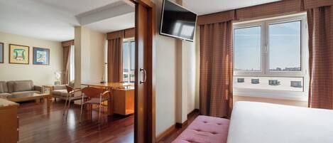 Una habitación de hotel con cama, escritorio, silla, sofá y televisión.