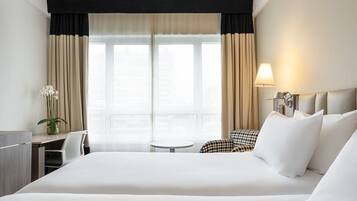 Une chambre d’hôtel avec un grand lit, un bureau, une chaise, une petite table et une lampe.
