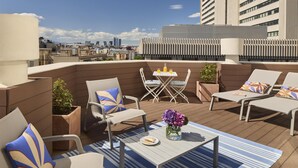 A rooftop terrace with outdoor seating, a table with a vase of flowers, and a city view. - NH Madrid Balboa (Madrid)