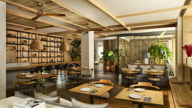 A modern restaurant with wooden tables and chairs, a variety of decorative plates, and a ceiling fan. - NH Madrid Balboa (Madrid)